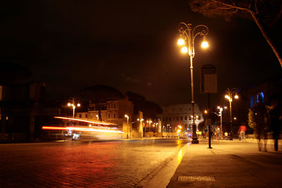 Illuminated street light in city against sky at night