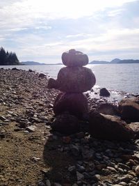 Stone stack on rock in sea against sky