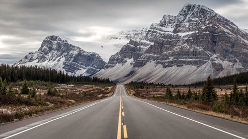 Road by snowcapped mountains against sky