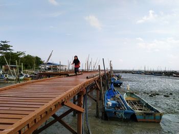 Rear view of man on boat moored in sea against sky