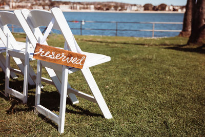 Information sign on field, reserved sign on white wooden chair on the lawn