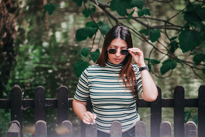 Young woman using mobile phone while standing on railing