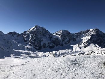 Scenic view of snowcapped mountains against clear blue sky