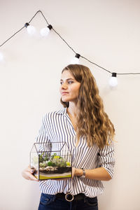 Young woman looking away while standing on table