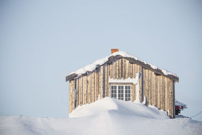 Snow covered building against clear sky