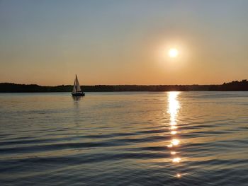 Sailboat sailing on sea against sky during sunset