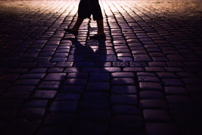 Low section of woman standing on cobblestone