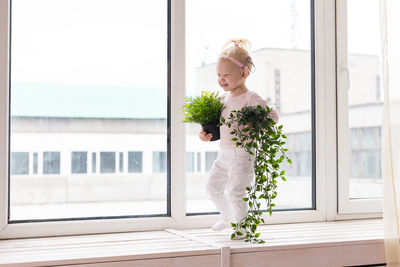 Portrait of young woman standing by window