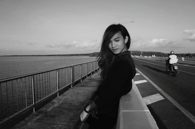 Portrait of young woman playing in sea against sky