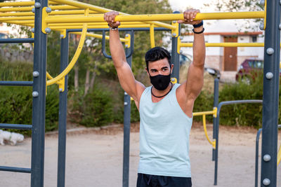 Athletic male exercising chin-ups in playground