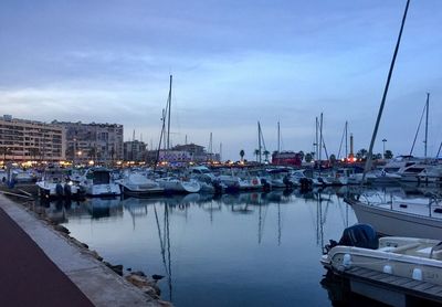 Boats moored at harbor against sky