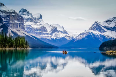 Scenic view of lake by snowcapped mountains against sky