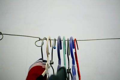 Close-up of clothespins hanging on clothesline against wall