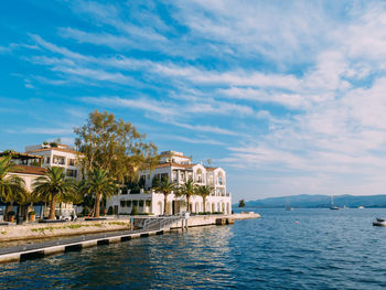 Buildings at waterfront against cloudy sky