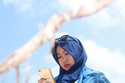 Woman using mobile phone against sky