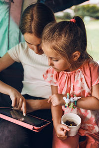 Two girls sisters spending family time in a tent on camping. children using tablet playing games