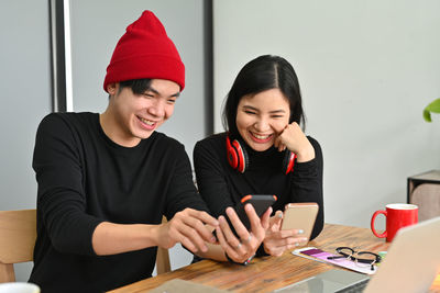 Smiling young woman using smart phone on table