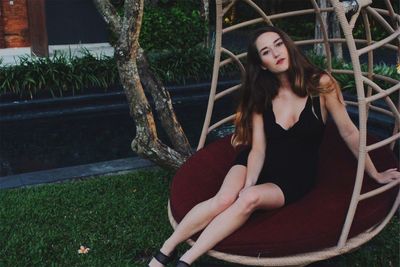 Portrait of smiling young woman sitting on tree