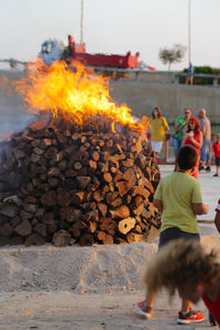 People standing by bonfire on street against sky