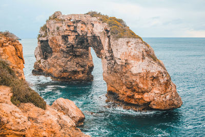 Rock formation in sea against sky