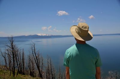 Rear view of man standing by sea against sky