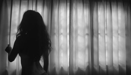 Woman standing in front of curtain