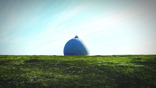 Grassy field against cloudy sky