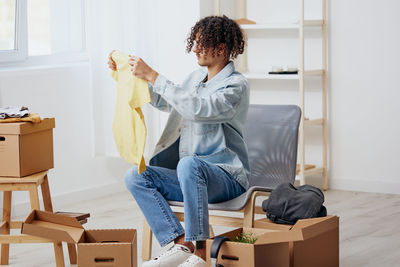 Portrait of young woman sitting on suitcase