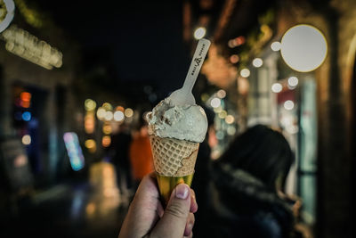 Human hand holding ice cream cone at night
