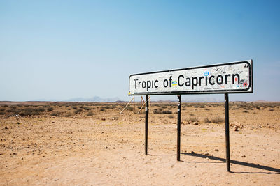 Information sign on field against clear sky. tropic of capricorn