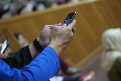 Midsection of man holding mobile phone