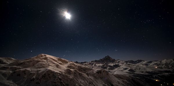 Scenic view of snowcapped mountains against sky at night