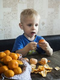 Boy having oranges while sitting on sofa at home