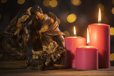 Close-up of statues and lit candles on table