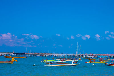 Boats moored in sea against blue sky