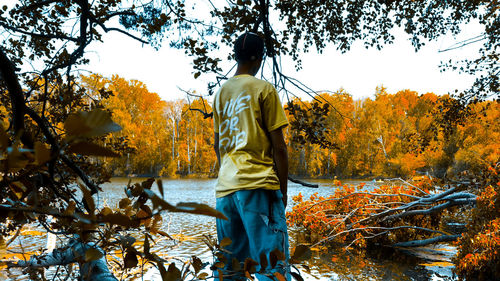 Rear view of man standing by plants during autumn