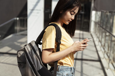 Young woman using mobile phone while standing indoors