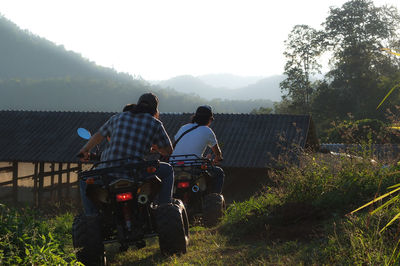 Rear view of people riding quadbikes on land