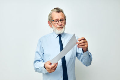 Senior man holding paper against white background