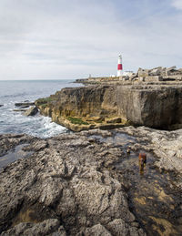 Lighthouse on beach by sea against sky