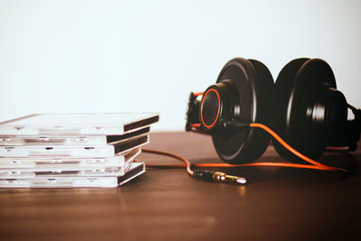 Close-up of headphones and stacked compact discs on table