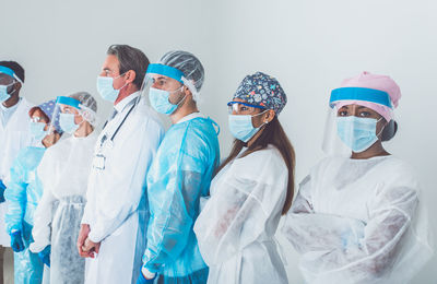 Portrait of doctors wearing mask standing against white background