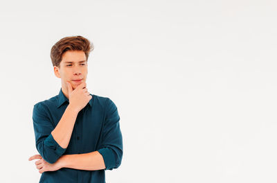 Young man looking away against white background