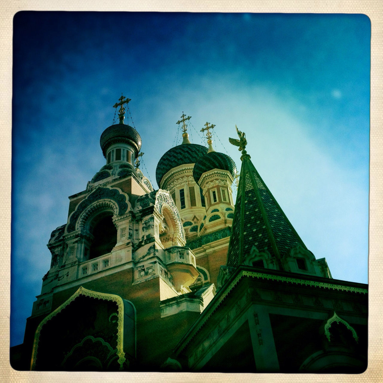 transfer print, religion, place of worship, spirituality, church, architecture, low angle view, built structure, building exterior, sky, auto post production filter, blue, cathedral, dome, cross, famous place, tower, day