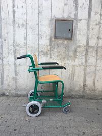 Empty wheelchair against wall