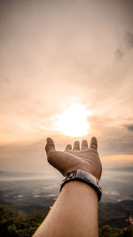 Close-up of hand gesturing against sky during sunset