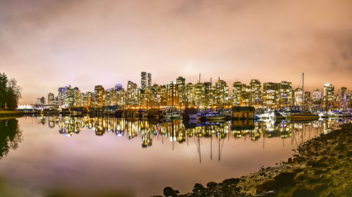 Panoramic view of illuminated buildings by river against sky