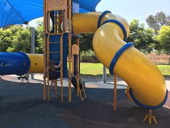 Close-up of yellow playground against blue sky