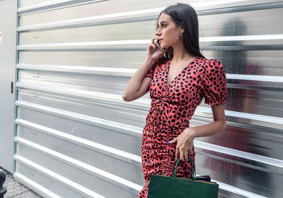 Woman looking away while standing against wall