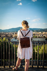 Rear view of woman standing on railing against mountain